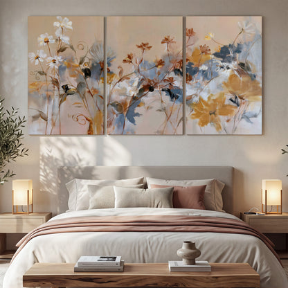 Loose blue and ochre blossoms layered across a warm neutral background 3 piece canvas wall art displayed in a bedroom