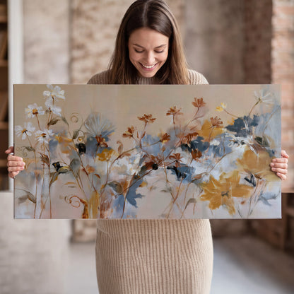 Loose blue and ochre blossoms layered across a warm neutral background single canvas wall art held in hands