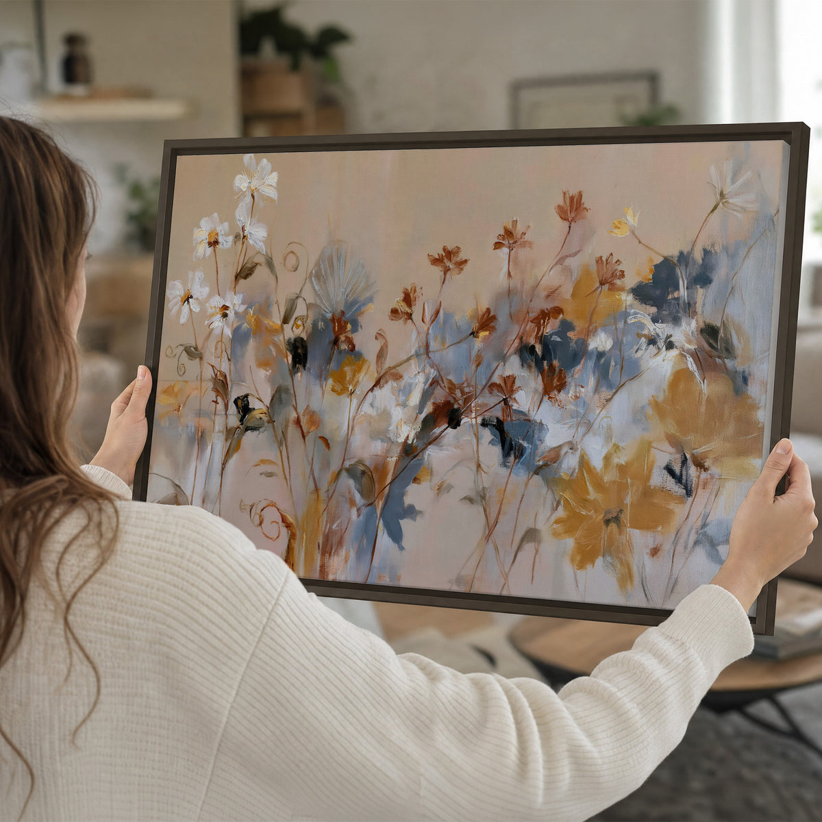 Loose blue and ochre blossoms layered across a warm neutral background single framed canvas wall art held in hands