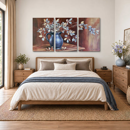 White flowering branches gathered in a deep blue pitcher against a warm rust-colored wall 3 piece canvas wall art styled in an interior