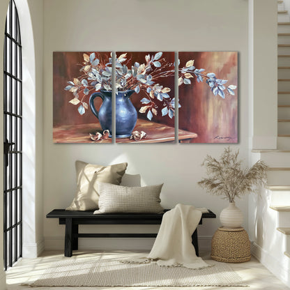 White flowering branches gathered in a deep blue pitcher against a warm rust-colored wall 3 piece canvas wall art displayed in a entryway
