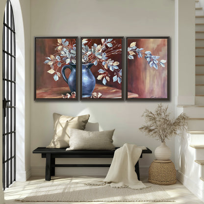 White flowering branches gathered in a deep blue pitcher against a warm rust-colored wall 3 piece framed canvas wall art displayed in a entryway