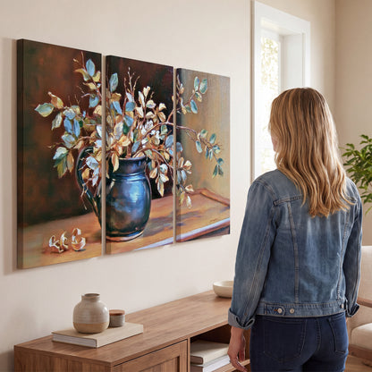 White and peach flowering branches arranged in a blue vase against a warm ochre background 3 piece canvas wall art three panel arrangement on a wall
