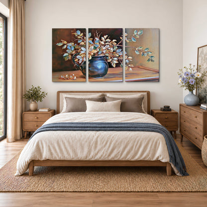 White and peach flowering branches arranged in a blue vase against a warm ochre background 3 piece canvas wall art styled in an interior