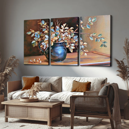 White and peach flowering branches arranged in a blue vase against a warm ochre background 3 piece canvas wall art displayed in a rustic living room