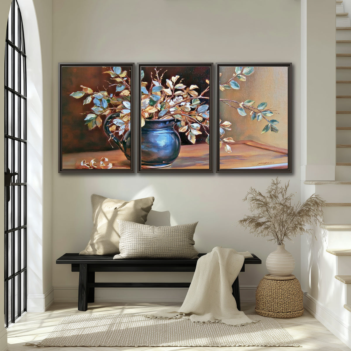 White and peach flowering branches arranged in a blue vase against a warm ochre background 3 piece framed canvas wall art displayed in a entryway