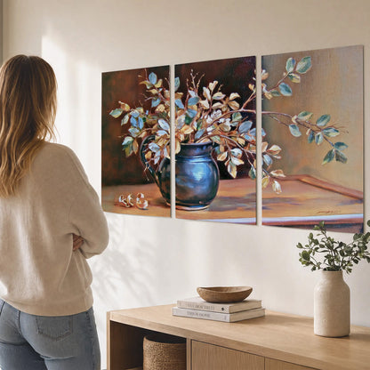 White and peach flowering branches arranged in a blue vase against a warm ochre background set of 3 poster prints three panel arrangement on a wall