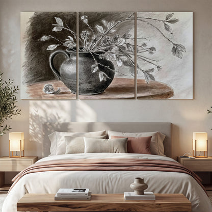 Fine leafy branches spilling from a dark rounded vase in a soft monochrome still life 3 piece canvas wall art displayed in a bedroom