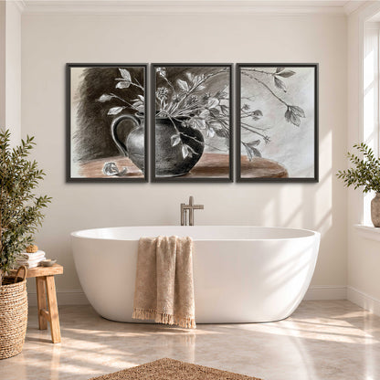 Fine leafy branches spilling from a dark rounded vase in a soft monochrome still life 3 piece framed canvas wall art styled in an interior