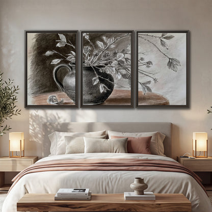Fine leafy branches spilling from a dark rounded vase in a soft monochrome still life 3 piece framed canvas wall art displayed in a bedroom