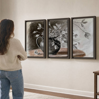 Fine leafy branches spilling from a dark rounded vase in a soft monochrome still life 3 piece framed canvas wall art three panel arrangement on a wall