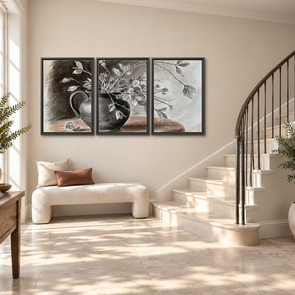 Fine leafy branches spilling from a dark rounded vase in a soft monochrome still life 3 piece framed canvas wall art styled in an interior