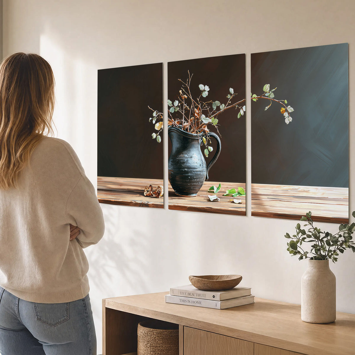A delicate arrangement of pale blossoms in a blue vase on a sunlit wooden table set of 3 poster prints three panel arrangement on a wall
