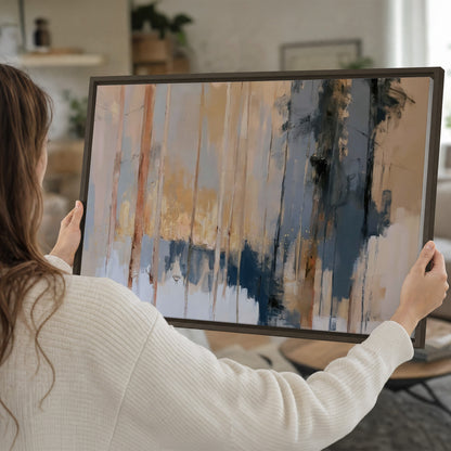 Vertical strokes of cream, blue and ochre suggesting a quiet woodland single framed canvas wall art held in hands