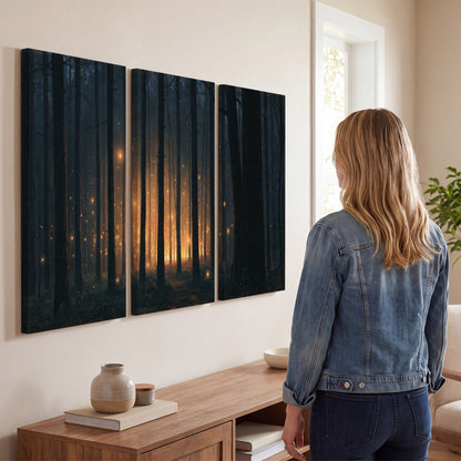 A warm amber glow shining between closely spaced dark forest trunks 3 piece canvas wall art three panel arrangement on a wall