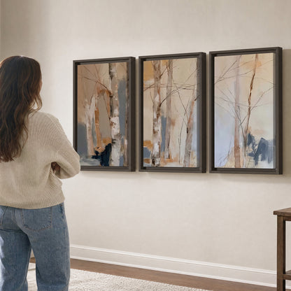 Loose pale blue, peach and cream strokes suggesting a stand of birch trees 3 piece framed canvas wall art three panel arrangement on a wall