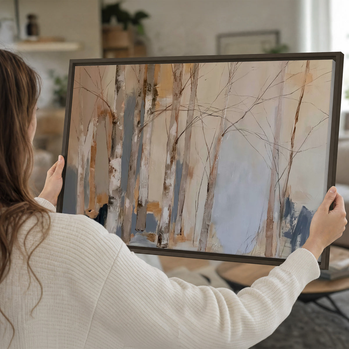 Loose pale blue, peach and cream strokes suggesting a stand of birch trees single framed canvas wall art held in hands
