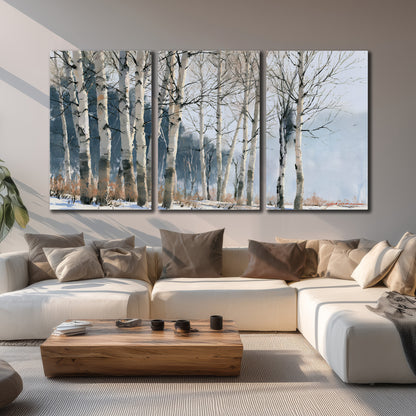 A line of bare birch trees against a cool blue-gray sky 3 piece canvas wall art displayed in a living room