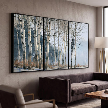 A line of bare birch trees against a cool blue-gray sky 3 piece framed canvas wall art displayed in a modern living room