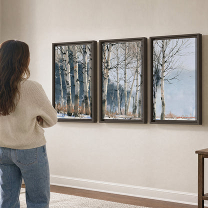 A line of bare birch trees against a cool blue-gray sky 3 piece framed canvas wall art three panel arrangement on a wall