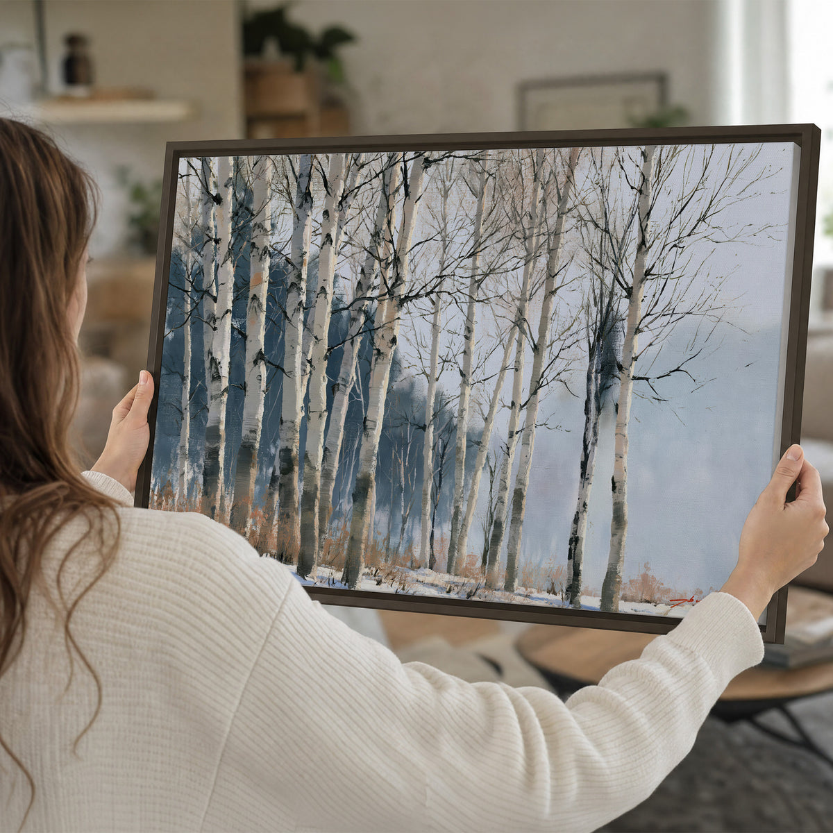 A line of bare birch trees against a cool blue-gray sky single framed canvas wall art held in hands
