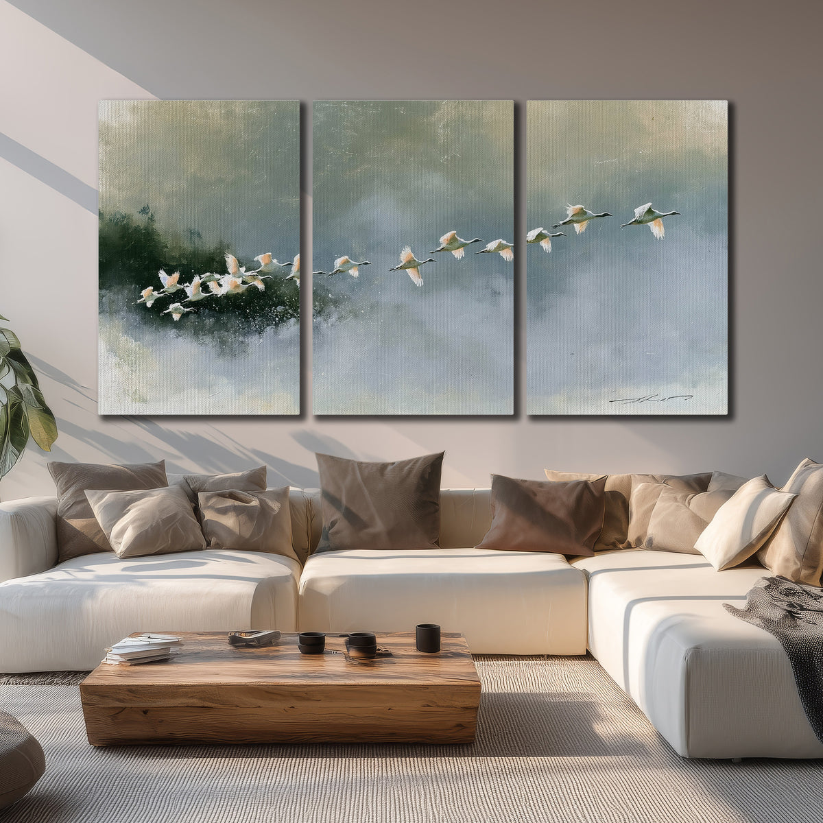 A flock of white birds flying low above a quiet blue-green lake 3 piece canvas wall art displayed in a living room