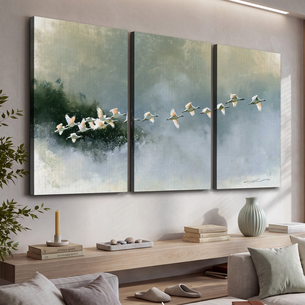 A flock of white birds flying low above a quiet blue-green lake 3 piece canvas wall art displayed in a console
