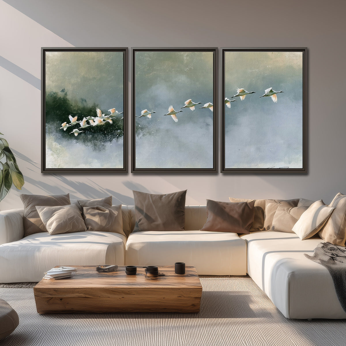 A flock of white birds flying low above a quiet blue-green lake 3 piece framed canvas wall art displayed in a living room