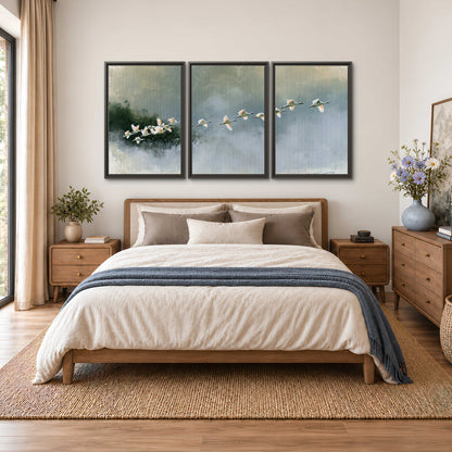 A flock of white birds flying low above a quiet blue-green lake 3 piece framed canvas wall art styled in an interior