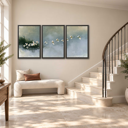 A flock of white birds flying low above a quiet blue-green lake 3 piece framed canvas wall art styled in an interior