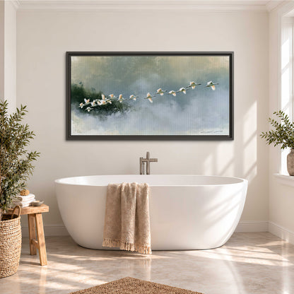 A flock of white birds flying low above a quiet blue-green lake single framed canvas wall art styled in an interior