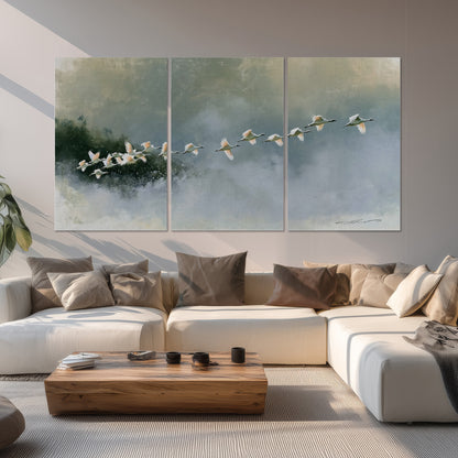 A flock of white birds flying low above a quiet blue-green lake set of 3 poster prints displayed in a living room