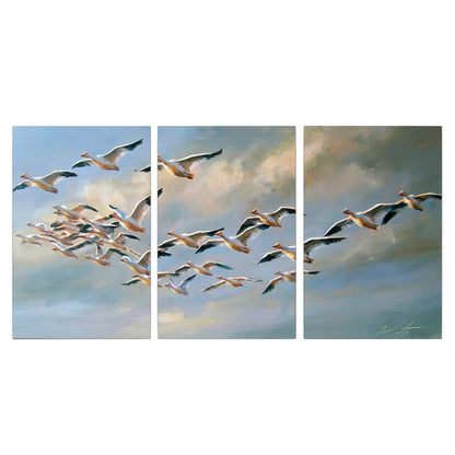 A flock of pale seabirds gliding beneath soft clouds across a blue sky 3 piece canvas wall art viewed straight on