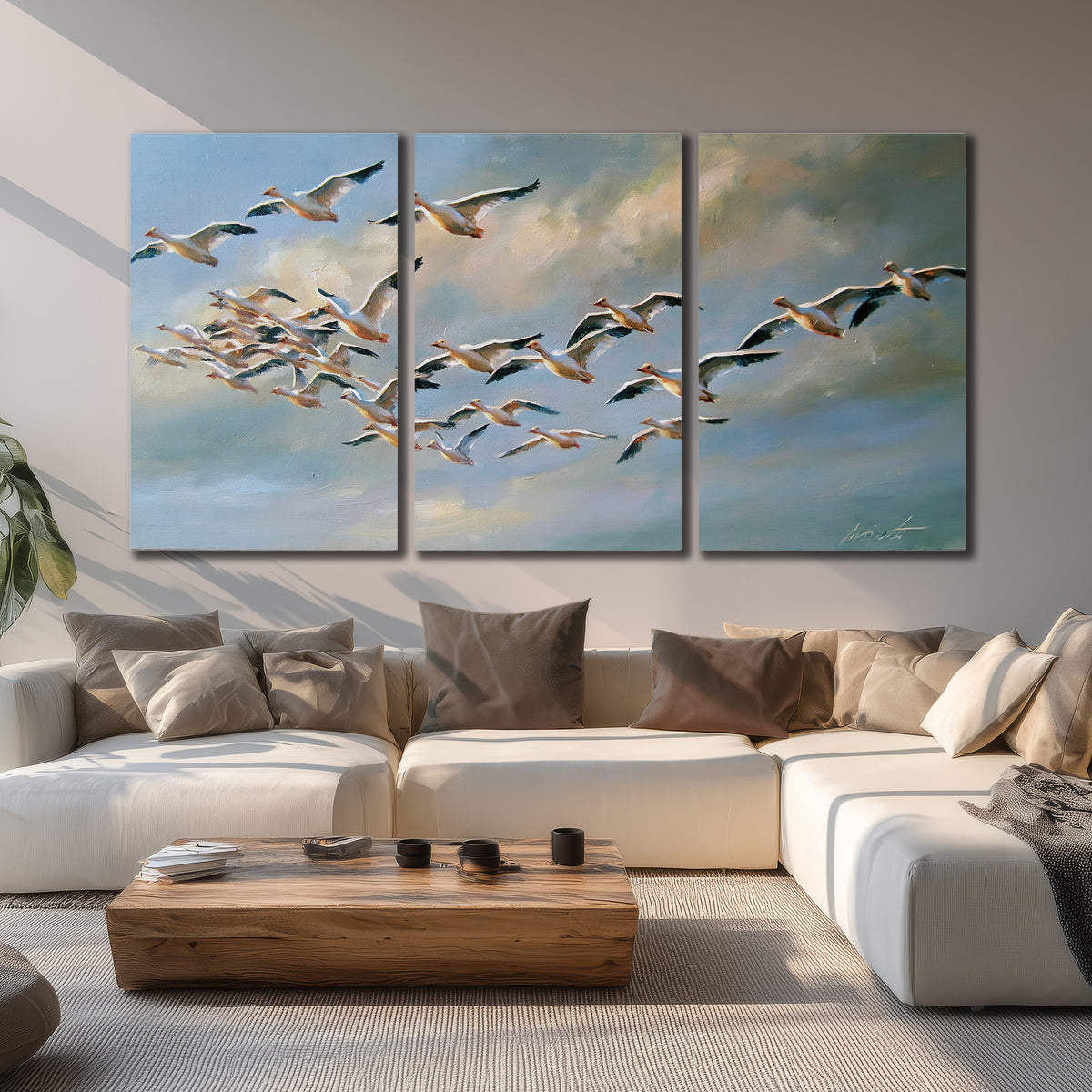 A flock of pale seabirds gliding beneath soft clouds across a blue sky 3 piece canvas wall art displayed in a living room