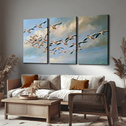 A flock of pale seabirds gliding beneath soft clouds across a blue sky 3 piece canvas wall art displayed in a rustic living room