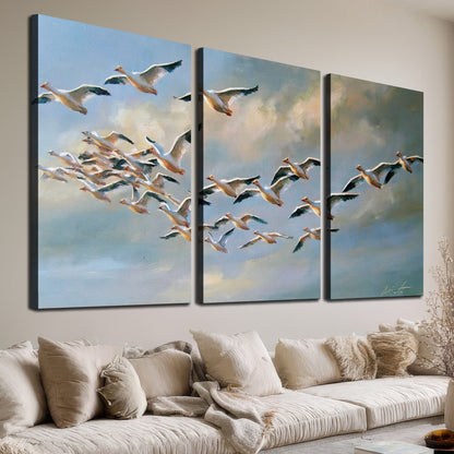 A flock of pale seabirds gliding beneath soft clouds across a blue sky 3 piece canvas wall art room and product view