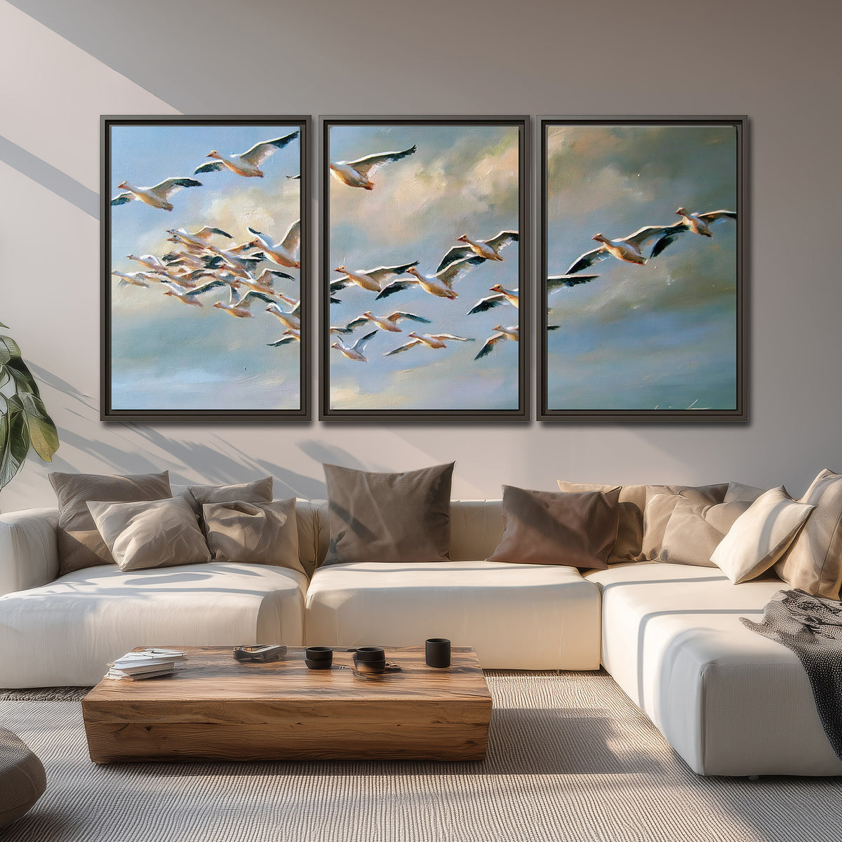 A flock of pale seabirds gliding beneath soft clouds across a blue sky 3 piece framed canvas wall art displayed in a living room