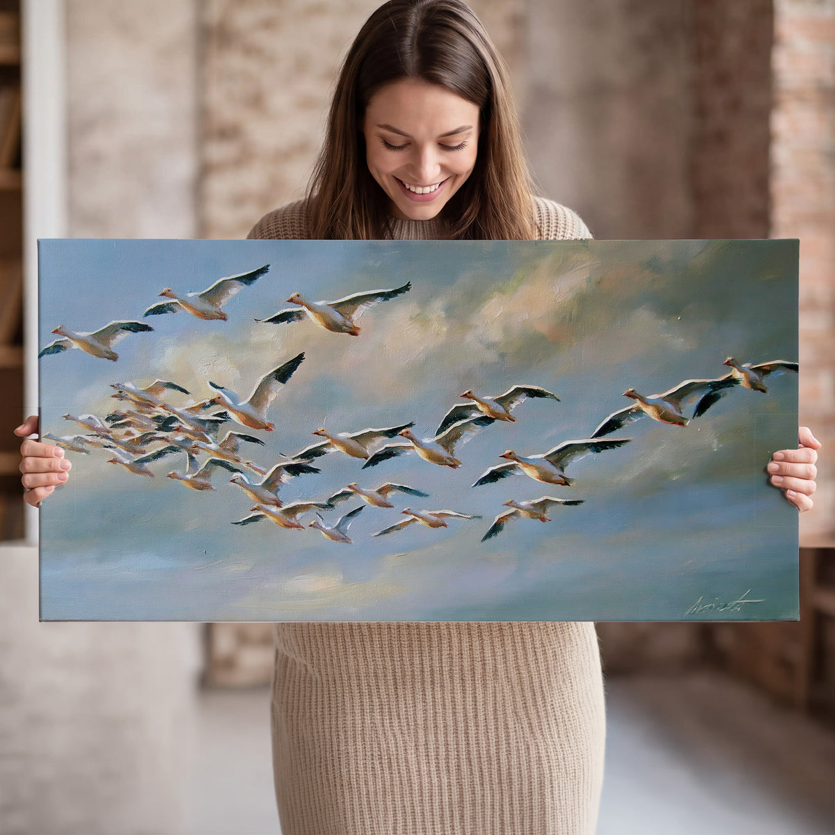 A flock of pale seabirds gliding beneath soft clouds across a blue sky single canvas wall art held in hands
