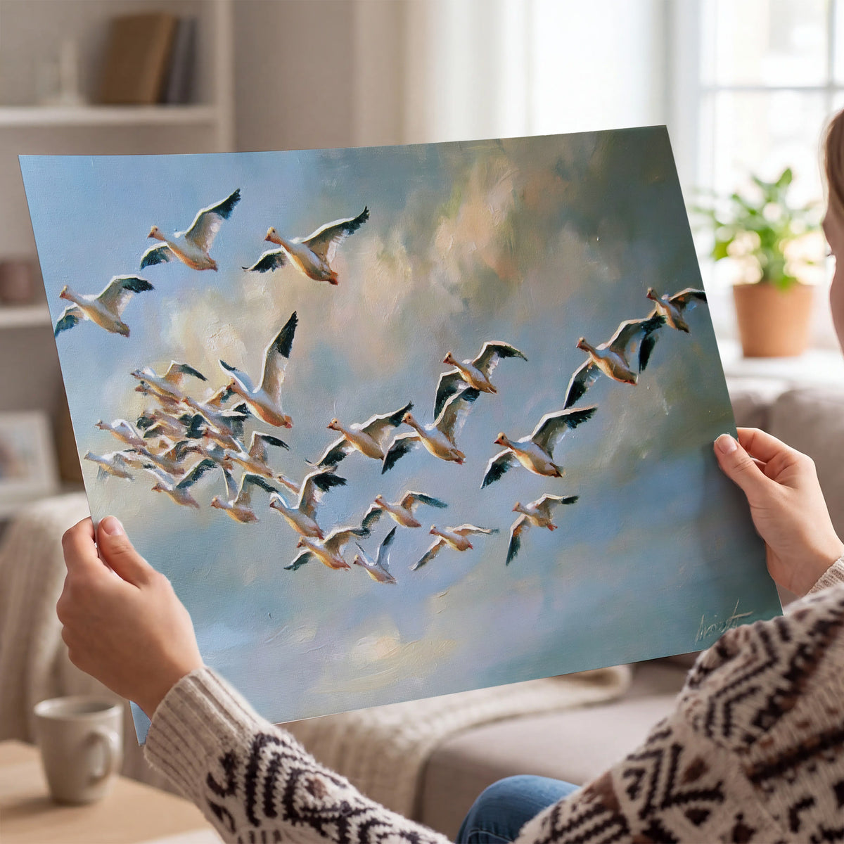 A flock of pale seabirds gliding beneath soft clouds across a blue sky single poster print held in hands