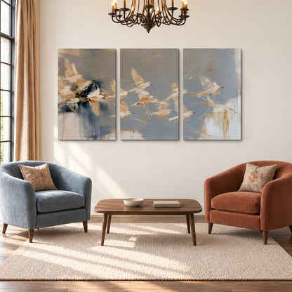Pale bird-like forms sweeping across layered strokes of blue, ochre and cream 3 piece canvas wall art styled in an interior