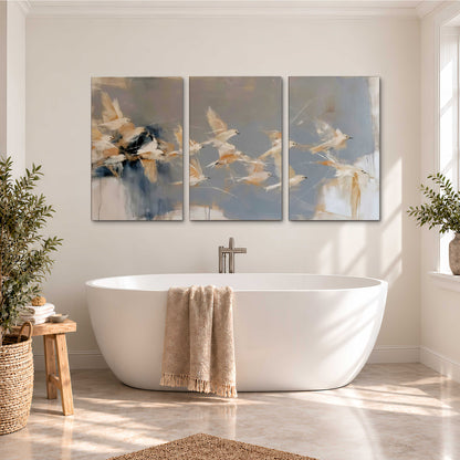 Pale bird-like forms sweeping across layered strokes of blue, ochre and cream 3 piece canvas wall art styled in an interior