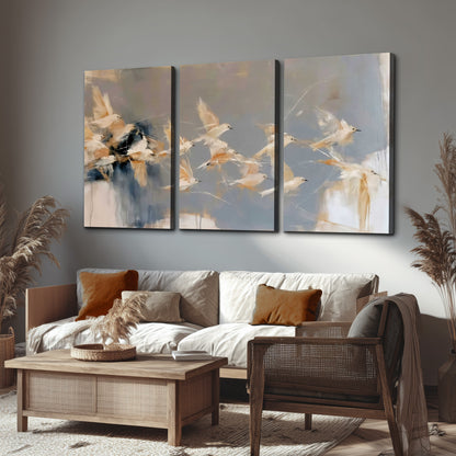 Pale bird-like forms sweeping across layered strokes of blue, ochre and cream 3 piece canvas wall art displayed in a rustic living room
