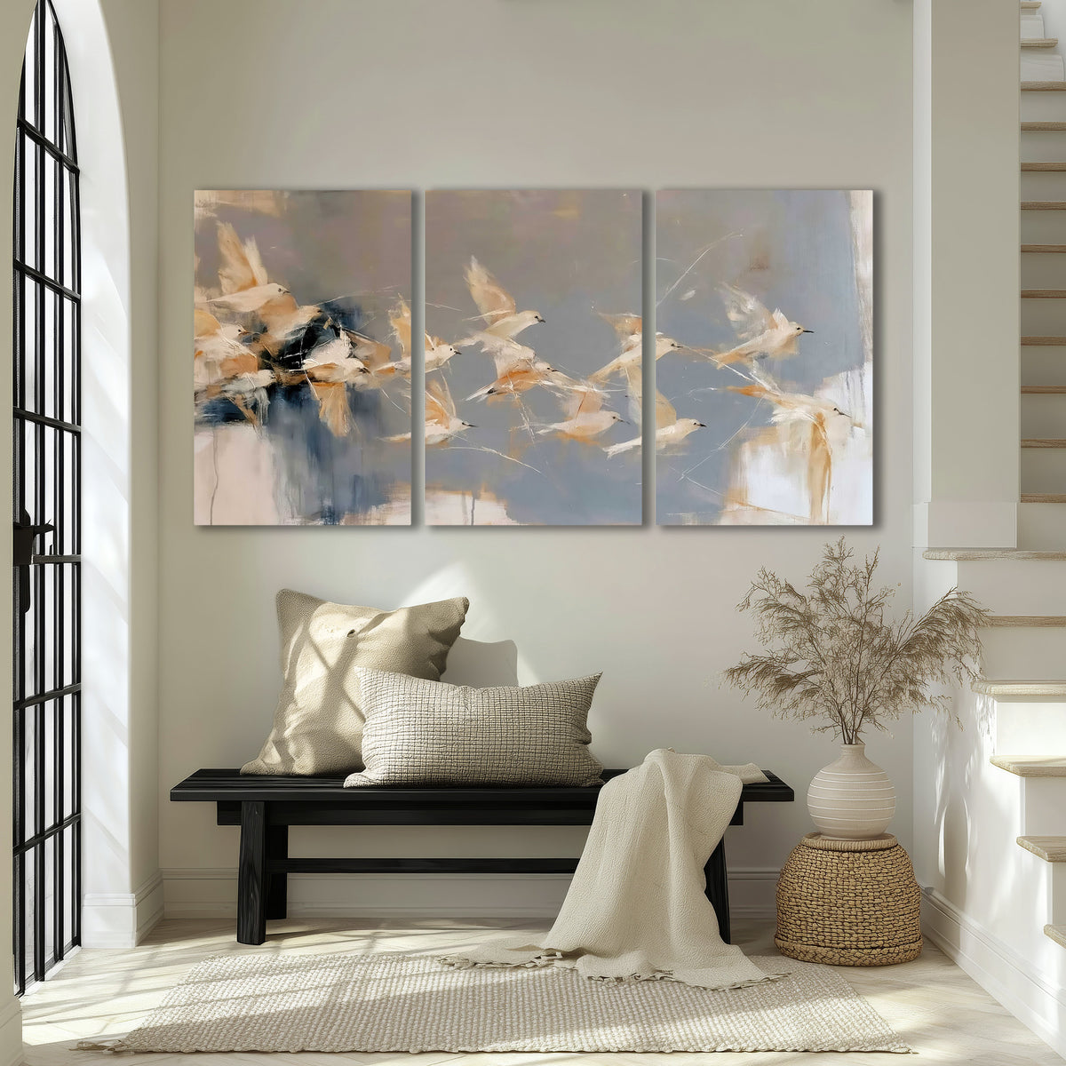 Pale bird-like forms sweeping across layered strokes of blue, ochre and cream 3 piece canvas wall art displayed in a entryway