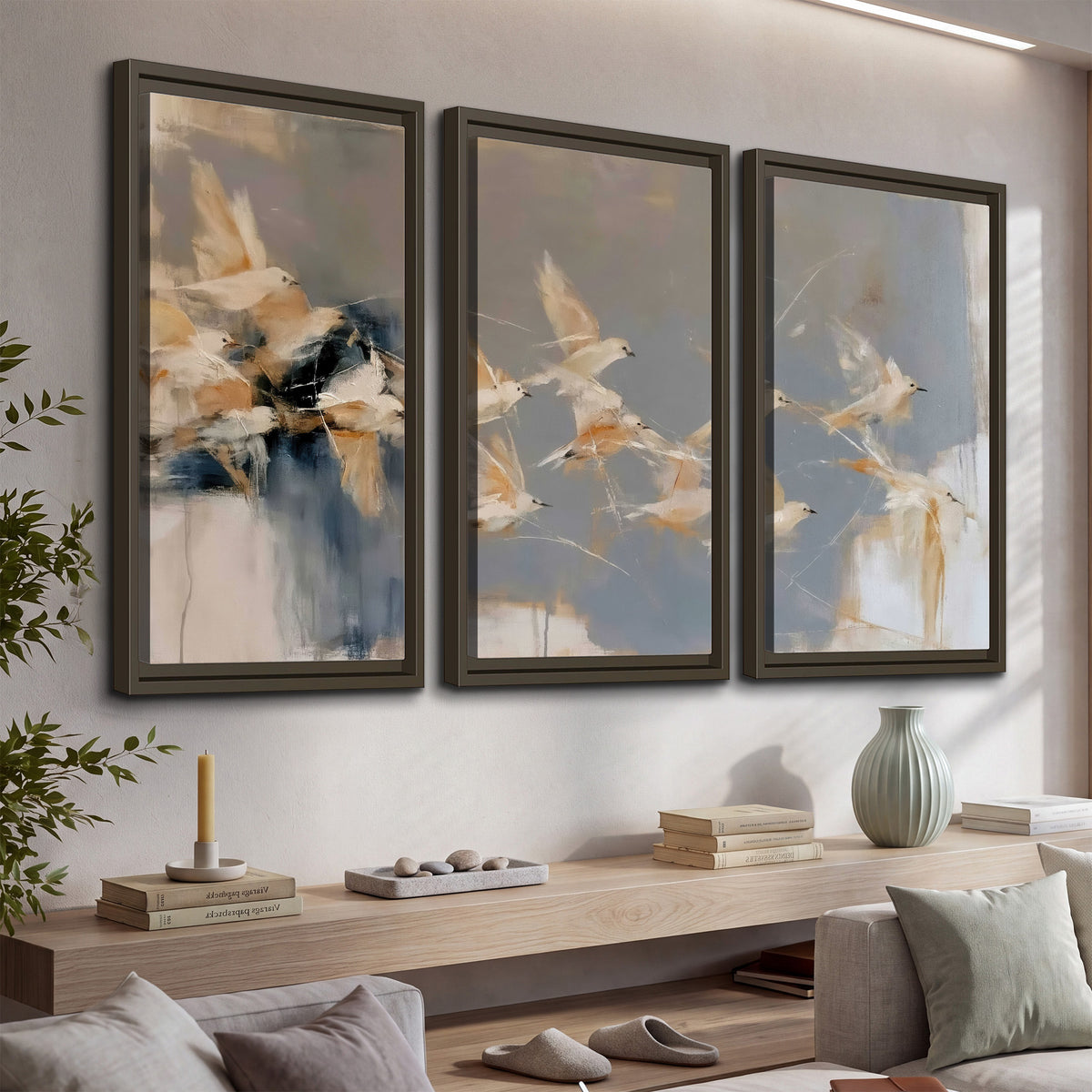 Pale bird-like forms sweeping across layered strokes of blue, ochre and cream 3 piece framed canvas wall art displayed in a console
