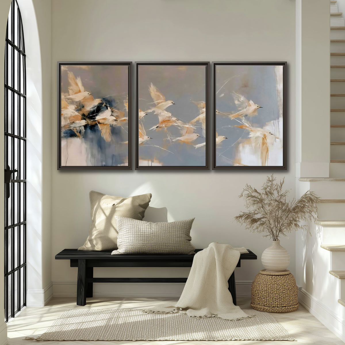 Pale bird-like forms sweeping across layered strokes of blue, ochre and cream 3 piece framed canvas wall art displayed in a entryway