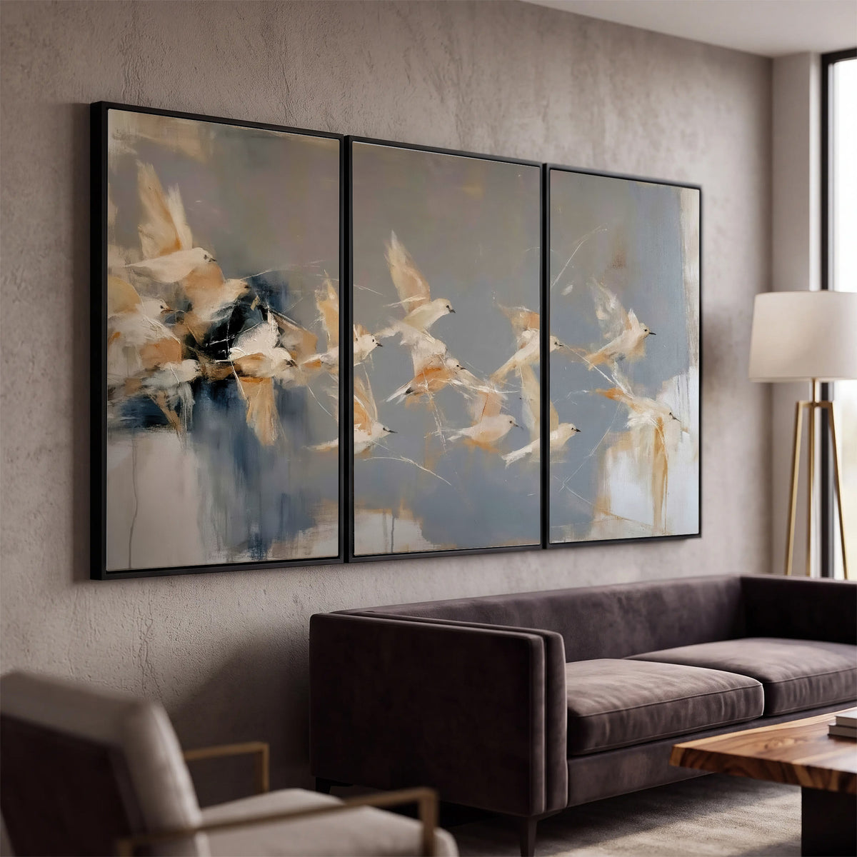 Pale bird-like forms sweeping across layered strokes of blue, ochre and cream 3 piece framed canvas wall art displayed in a modern living room
