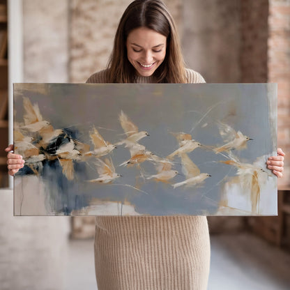 Pale bird-like forms sweeping across layered strokes of blue, ochre and cream single canvas wall art held in hands