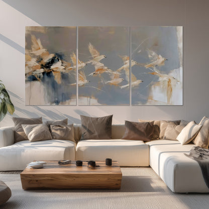 Pale bird-like forms sweeping across layered strokes of blue, ochre and cream set of 3 poster prints displayed in a living room