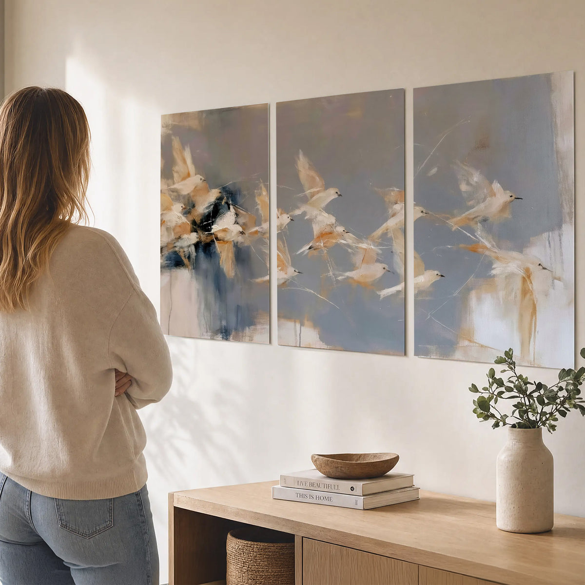 Pale bird-like forms sweeping across layered strokes of blue, ochre and cream set of 3 poster prints three panel arrangement on a wall