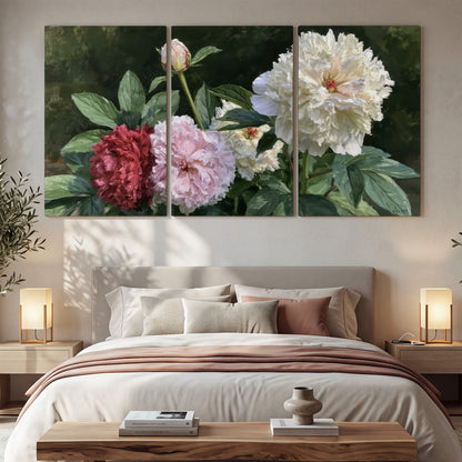 Cream, blush and red peonies surrounded by fresh green leaves 3 piece canvas wall art displayed in a bedroom